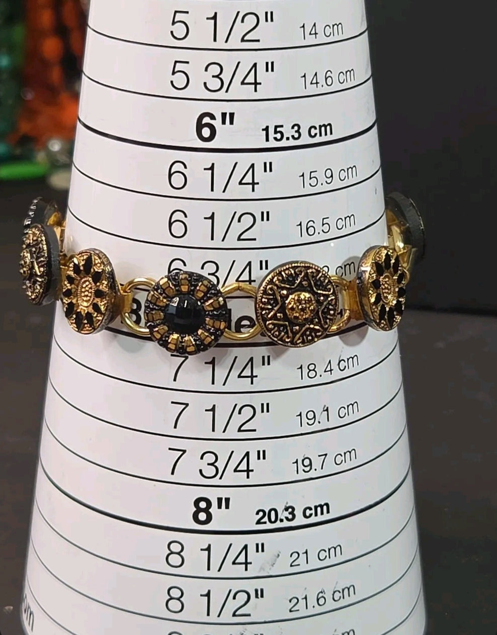 Oddly Darling Vintage link bracelet with gold-tone floral medallions and black faceted glass stones on a sizing cone.