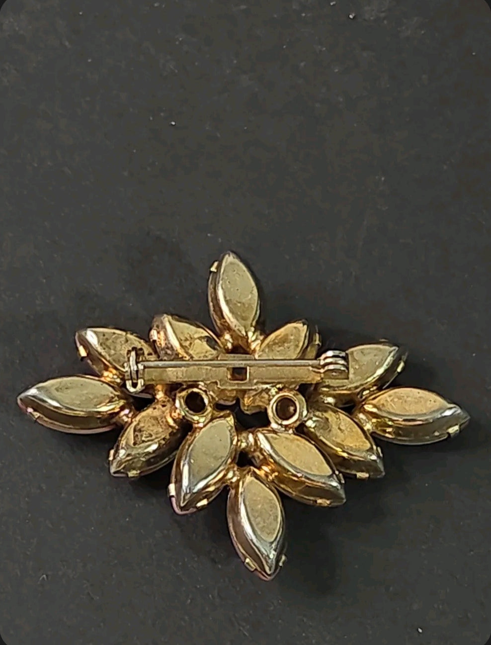 Back view of an Oddly Darling Vintage marquise stone cluster brooch with a gold-tone pin closure on a dark background.