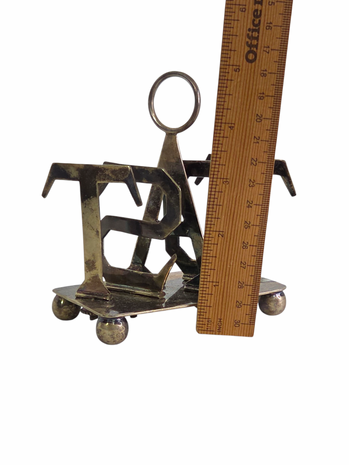 Oddly Darling Vintage metal toast rack with TOAST lettering, central ring handle, and ball feet, measured by a ruler.