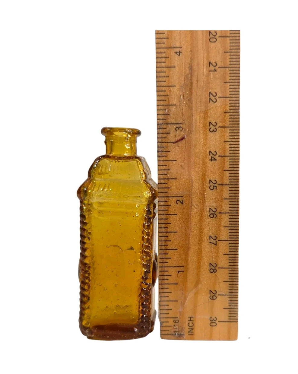 Oddly Darling Vintage miniature square amber glass apothecary bottle with textured edges next to a wooden ruler