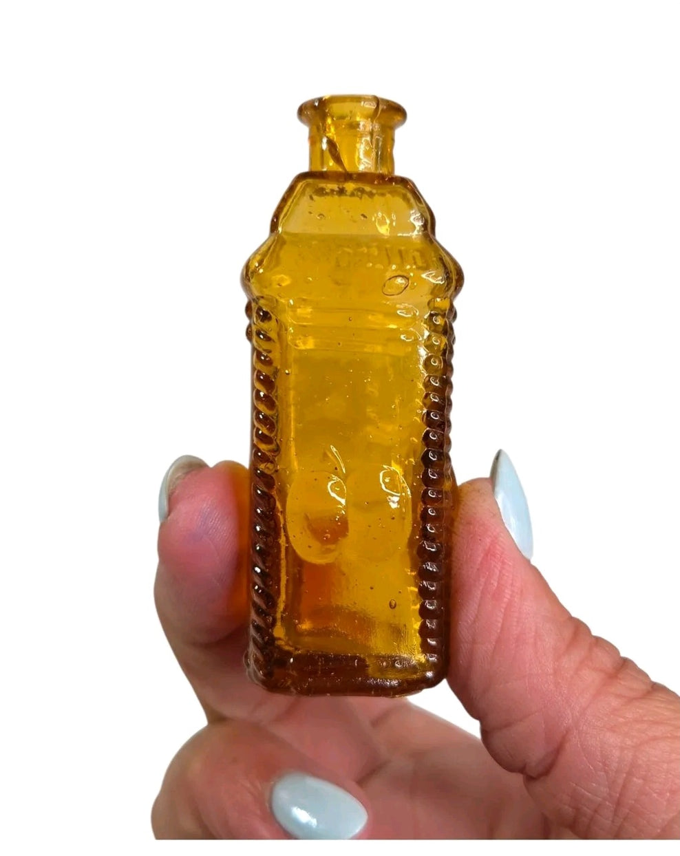 Oddly Darling Vintage miniature square amber glass apothecary bottle with textured edges held in a hand