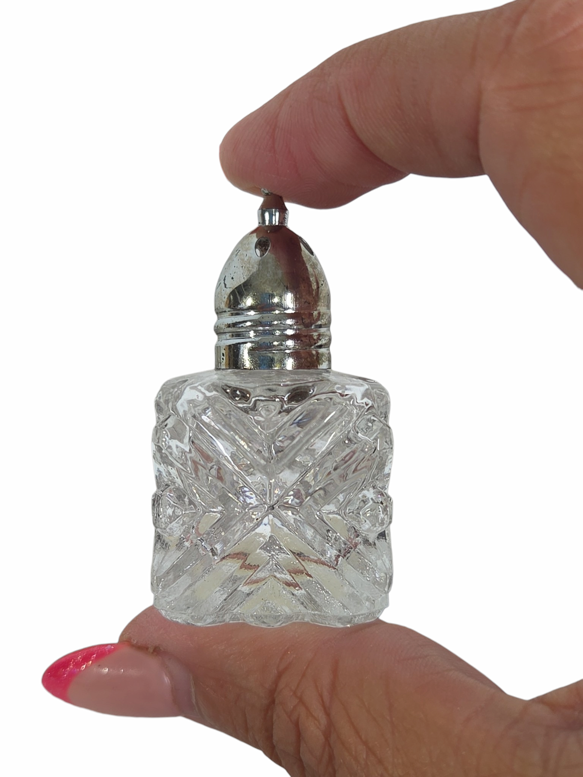 Oddly Darling Vintage miniature cut-glass salt and pepper shaker with a polished silver-plated lid held by fingers.