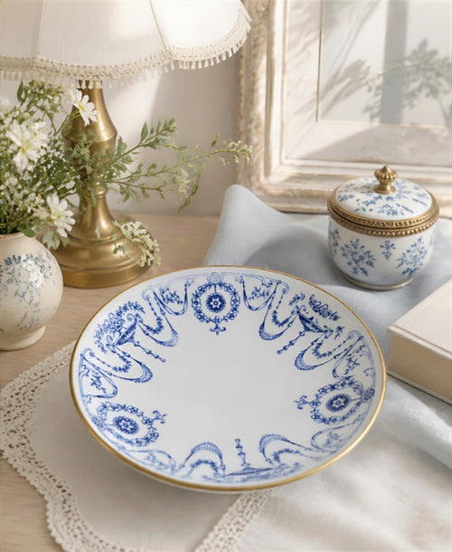 Oddly Darling Vintage Mintons porcelain dish with blue and white floral garlands and a gold-gilt rim on a lace doily.