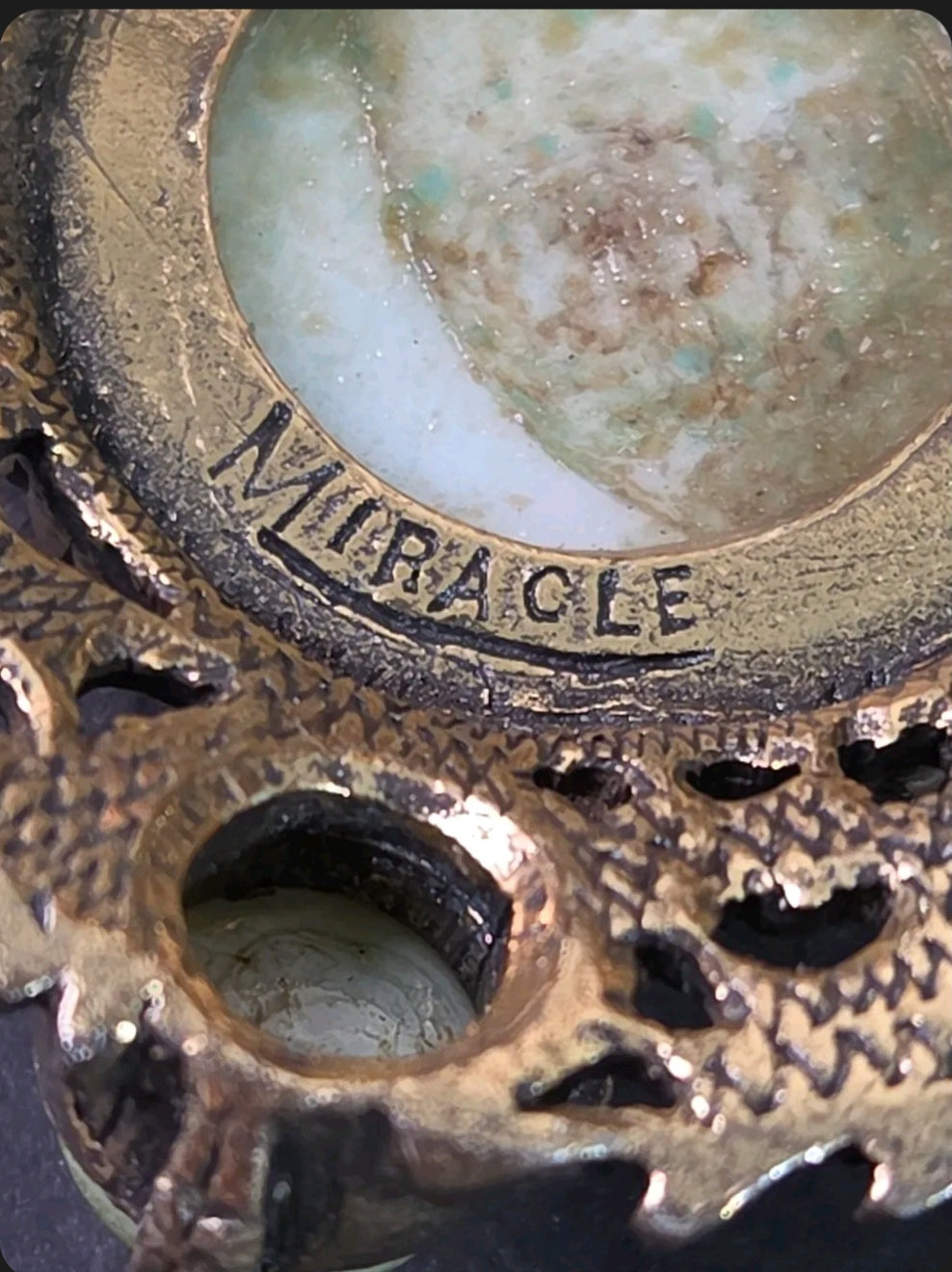 Oddly Darling Vintage Miracle brooch detail showing the signature hallmark on antique gold metal and green cabochon