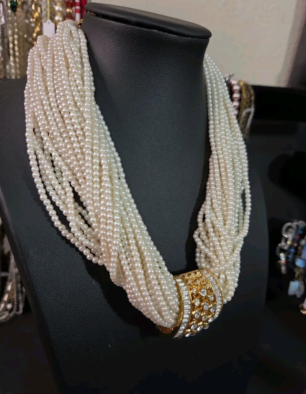 Oddly Darling Vintage multi-strand cream faux pearl necklace with a gold-tone rhinestone centerpiece on a display bust