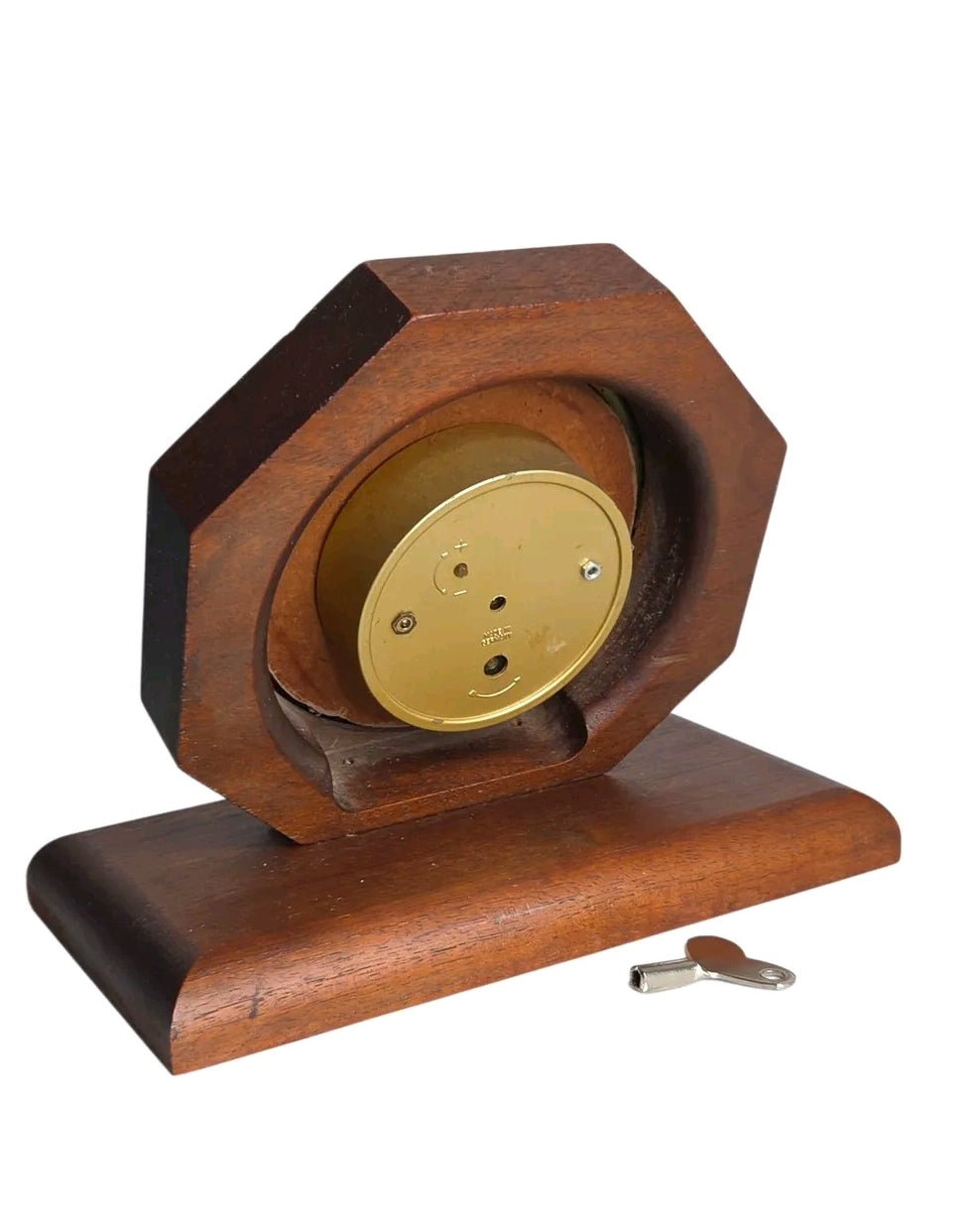 Back view of an Oddly Darling Vintage octagonal wooden mantel clock with a brass mechanism and winding key.