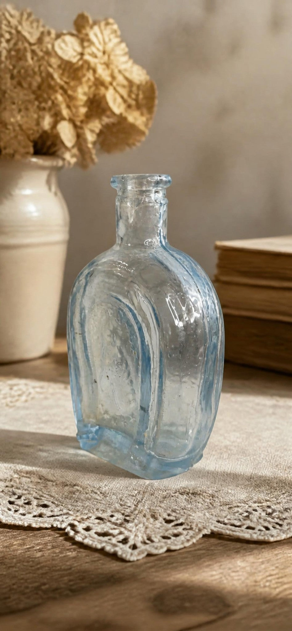 Oddly Darling Vintage miniature pale blue glass bottle with embossed detailing on a lace doily