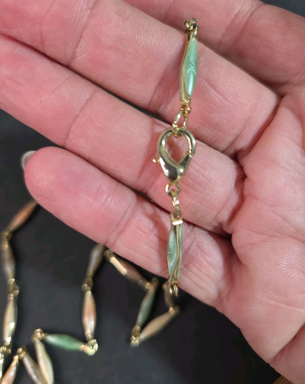 Oddly Darling Vintage multi-colored pastel beaded chain necklace with gold-tone hardware held in a hand