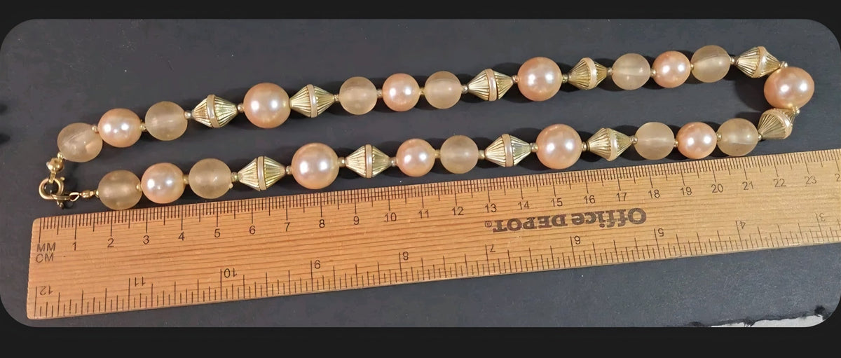 Oddly Darling Vintage statement necklace with peach faux pearls, frosted beads, and gold-tone fluted spacers on a ruler