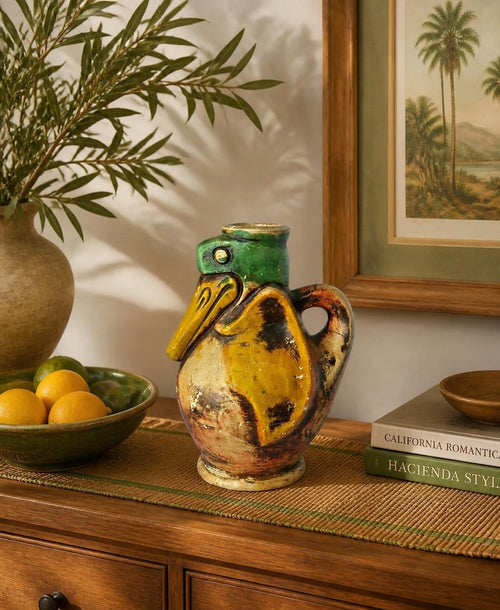 Oddly Darling Vintage ceramic pelican pitcher with hand-painted green and yellow glaze on a wooden console table.