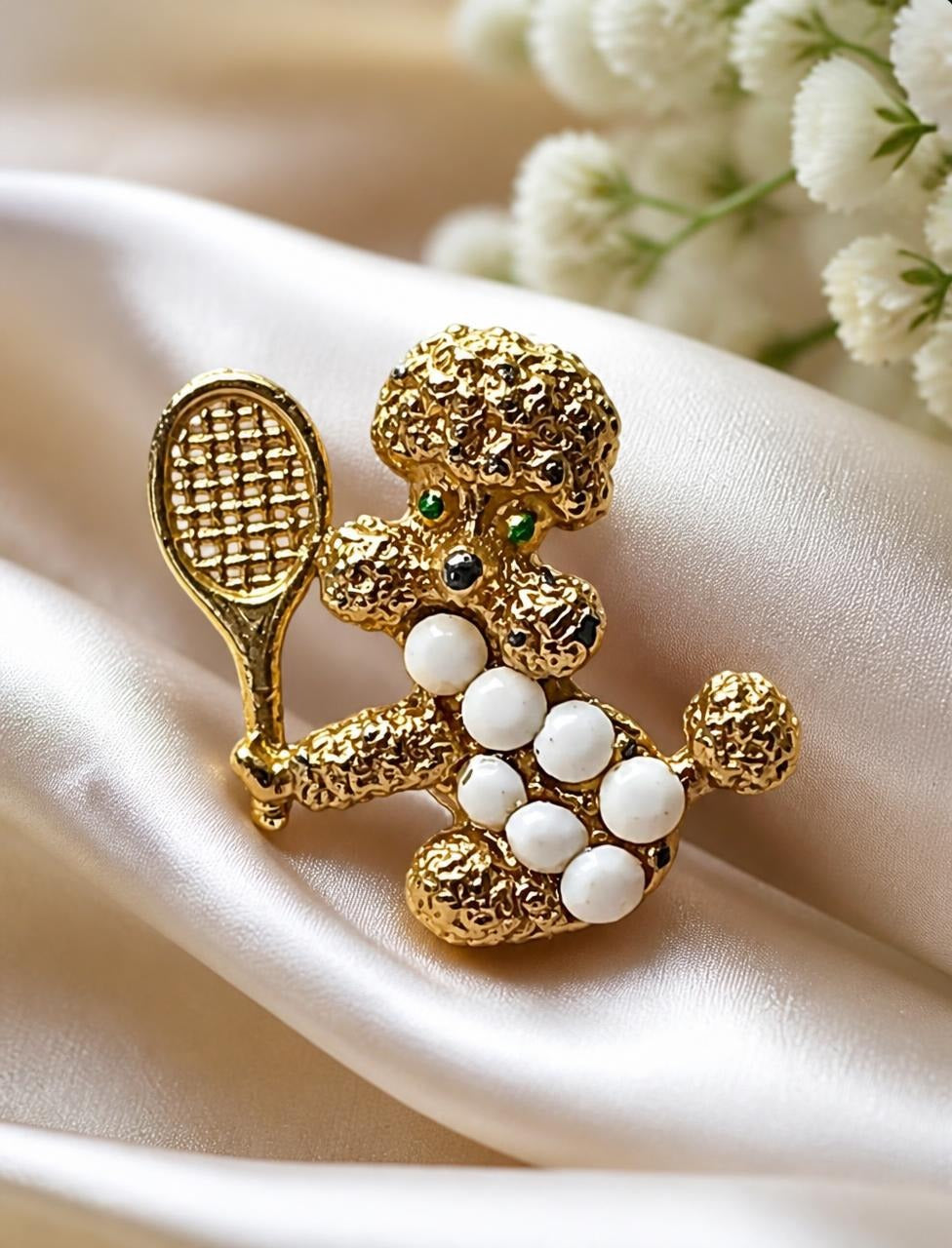 Oddly Darling Vintage gold-tone poodle tennis brooch with white milk glass stones, styled on satin fabric.