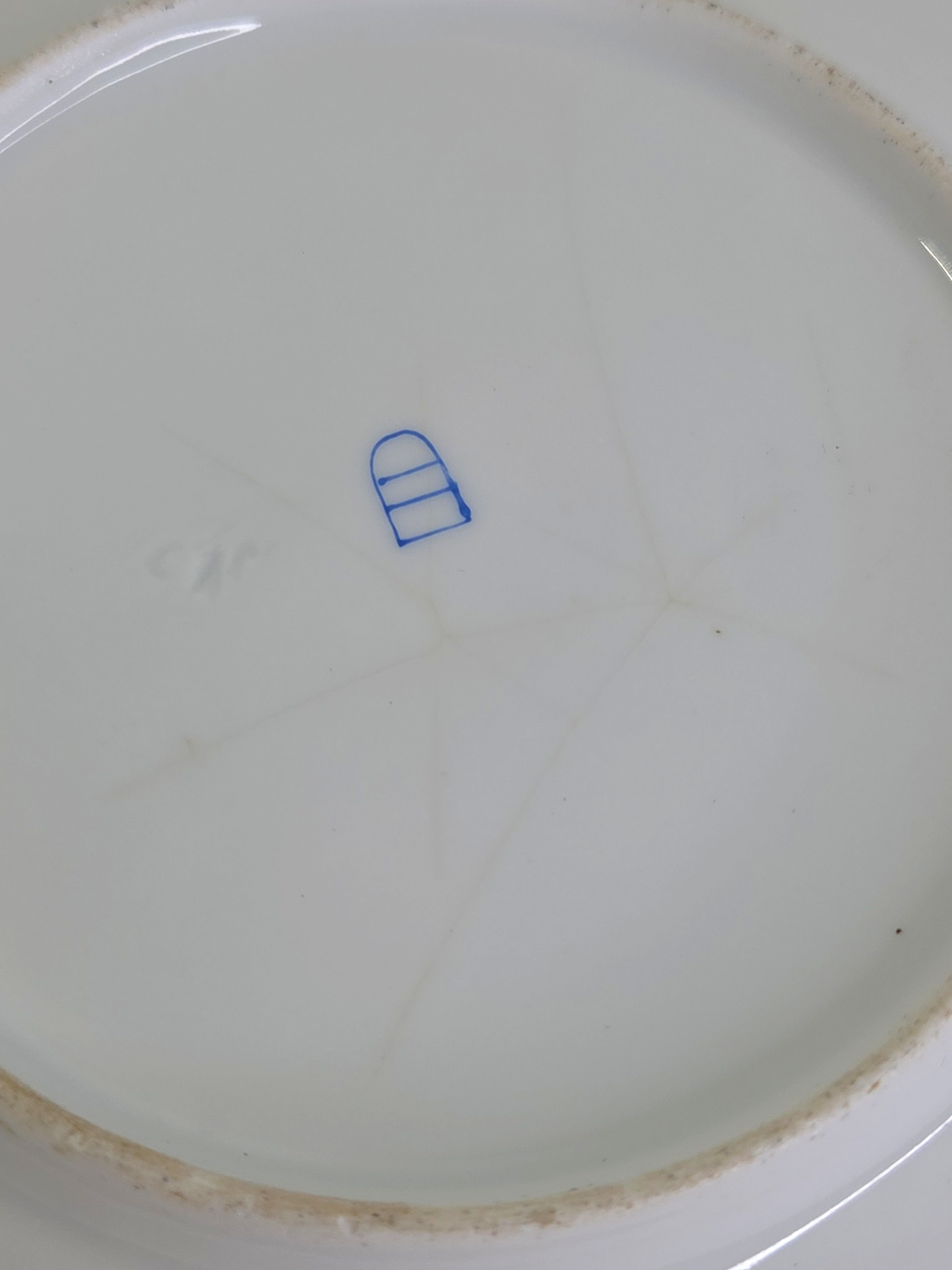 Oddly Darling Vintage porcelain plate base showing a blue maker mark and fine crazing on the white ceramic surface