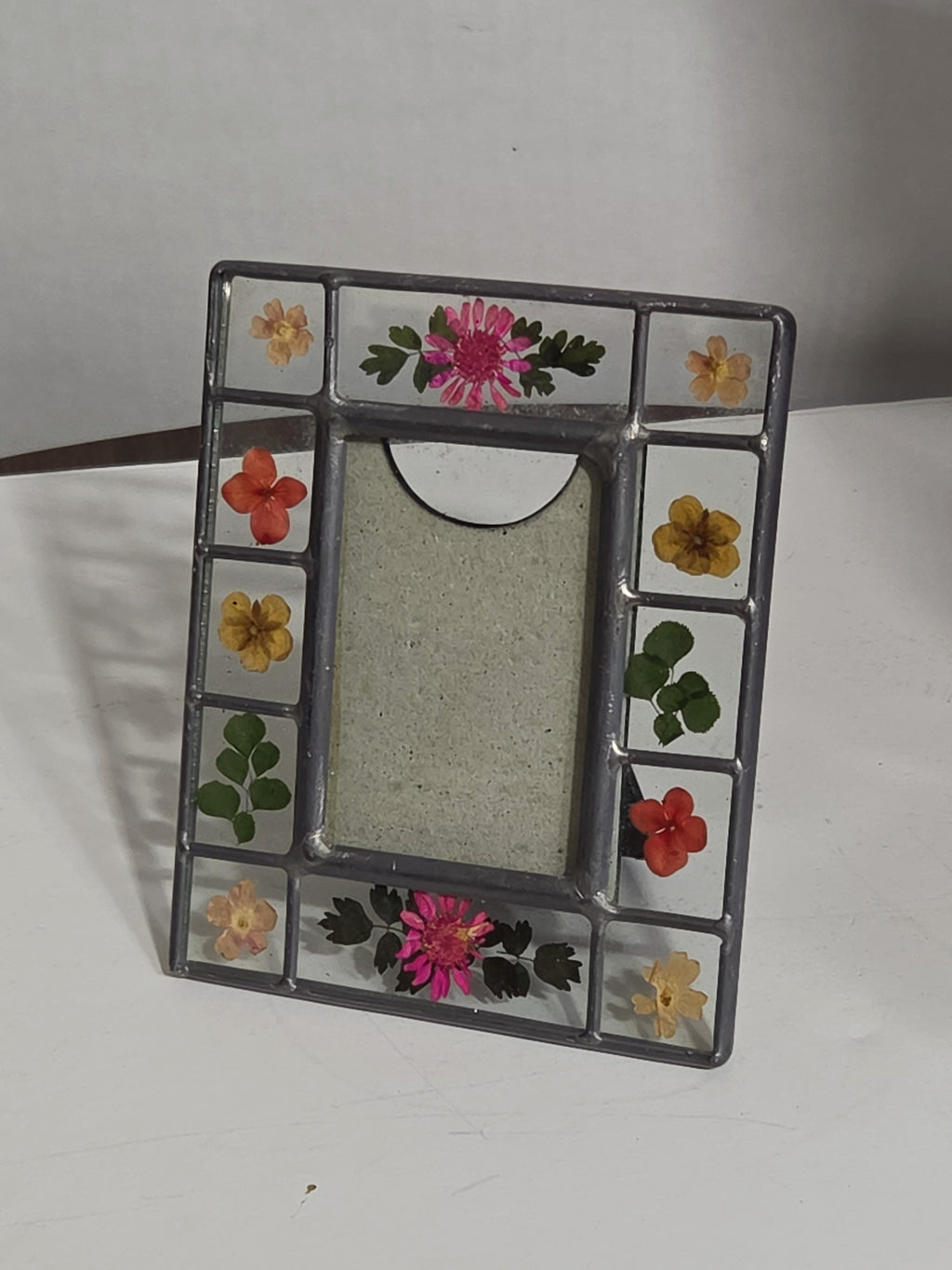 Oddly Darling Vintage pressed flower picture frame with stained-glass style metal border and colorful floral accents.