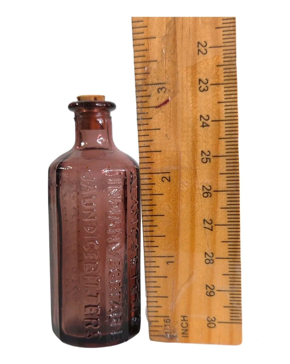 Oddly Darling Vintage purple embossed glass apothecary bottle with cork stopper next to a wooden ruler for scale.