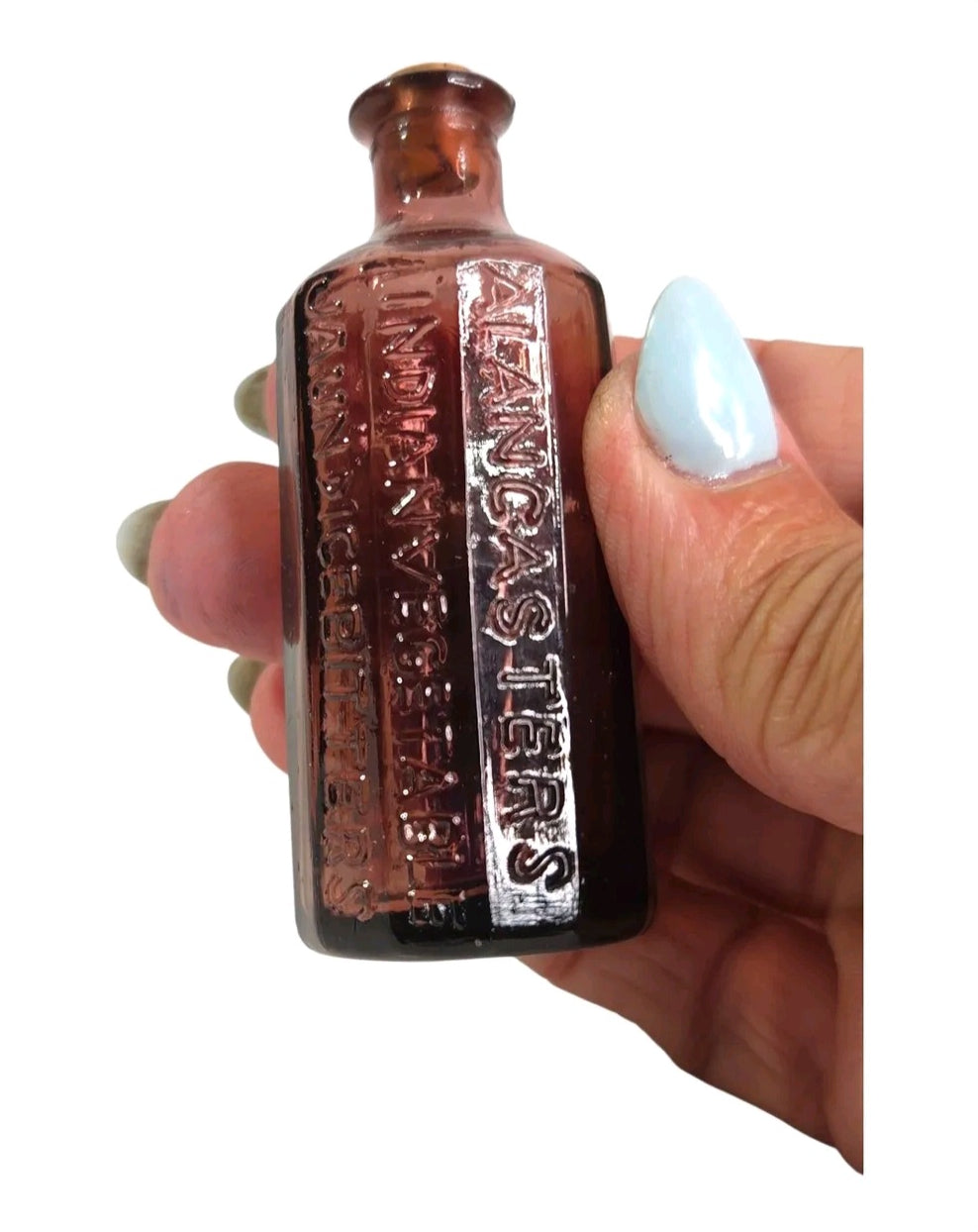 Oddly Darling Vintage small purple embossed glass apothecary bottle with cork stopper held in a hand