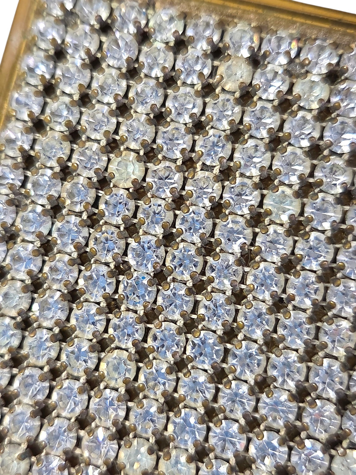 Close-up of the prong-set clear rhinestones on the vintage pave compact lid, a few stones cloudy