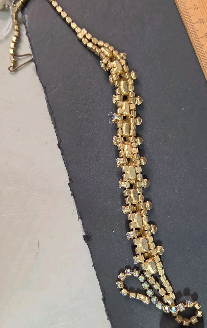 Oddly Darling Vintage gold-tone statement necklace with orange and iridescent rhinestones on a dark display surface.