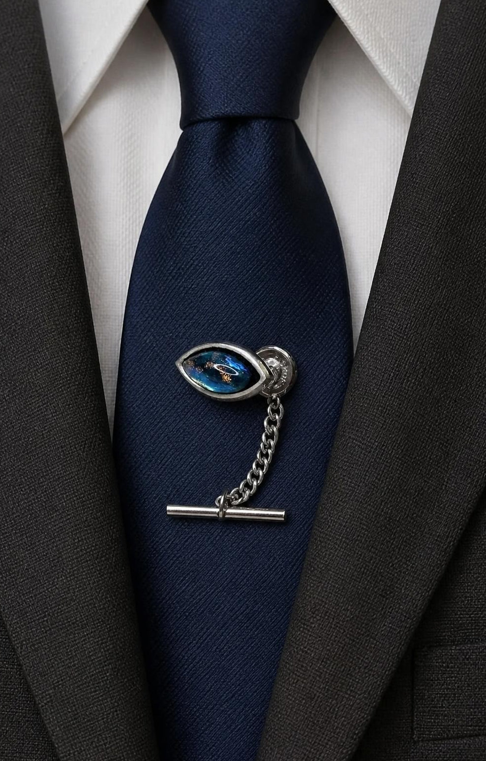 Oddly Darling Vintage silver-tone tie tack with a marquise-shaped iridescent blue stone and chain on a navy tie