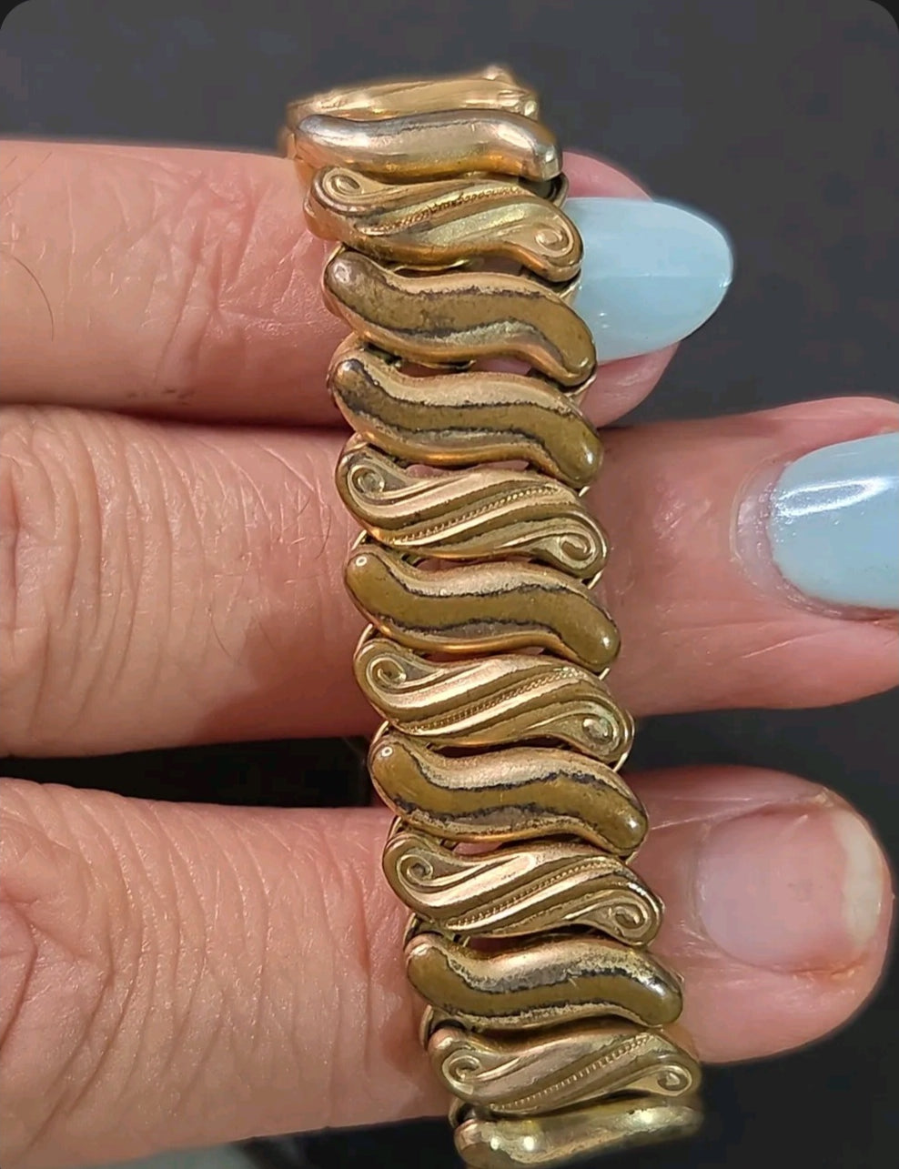 Oddly Darling Vintage Speidel gold-tone expansion bracelet with intricate wave-patterned links on a wrist.