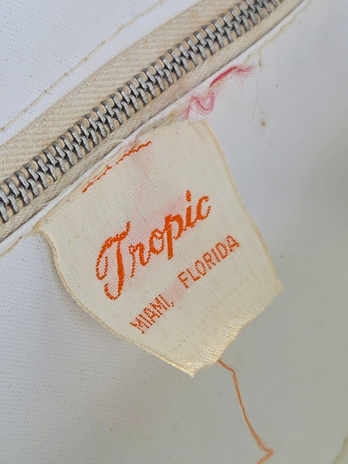 Close-up of the orange woven Tropic Miami Florida label below the zippered pocket