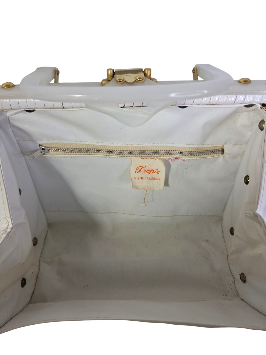 Inside the purse: white vinyl lining with zippered pocket and orange Tropic Miami Florida label, with some marks on the bottom