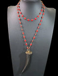 Oddly Darling Vintage long necklace with a black horn tusk pendant and vibrant red beaded rosary-style chain.