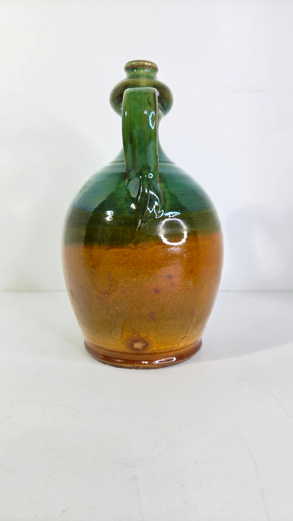 Oddly Darling Vintage handcrafted ceramic jug with a two-tone forest green and amber-brown glaze and dual handles.