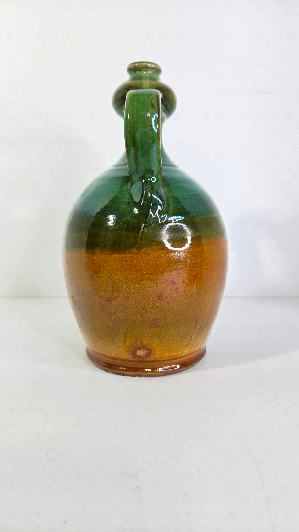 Oddly Darling Vintage handcrafted ceramic jug with a two-tone forest green and amber-brown glaze and dual handles.