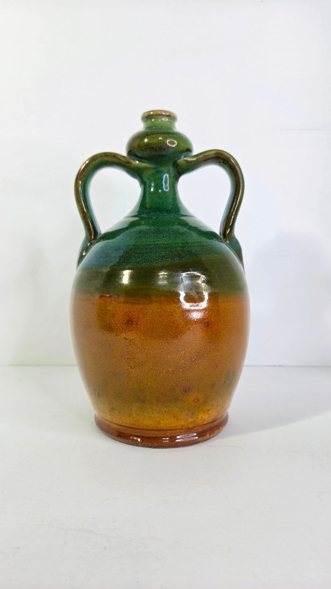 Oddly Darling Vintage handcrafted ceramic jug with two handles, featuring a forest green and amber-brown glaze.