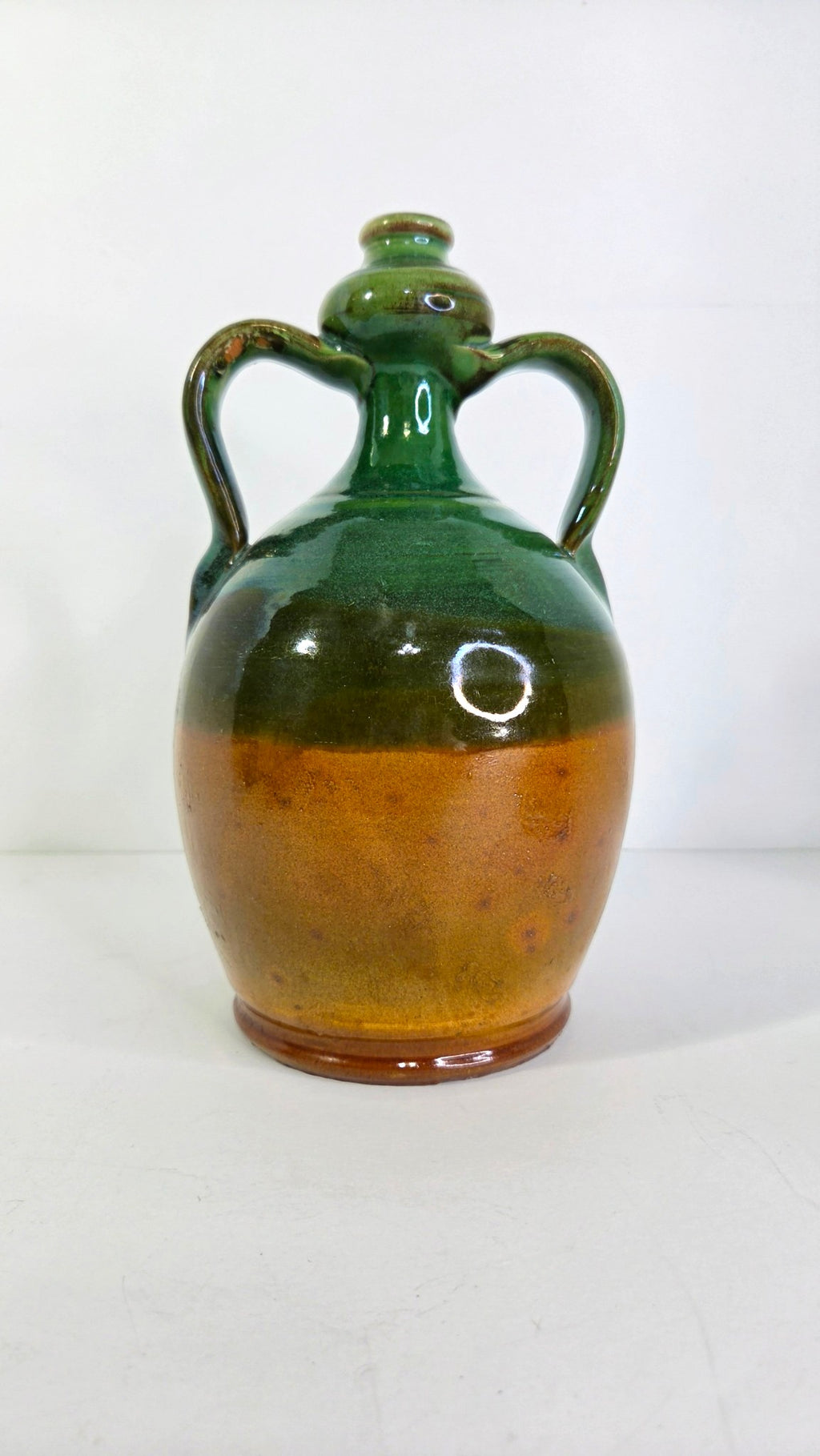 Oddly Darling Vintage handcrafted ceramic jug featuring a two-tone forest green and amber-brown glaze with two handles.
