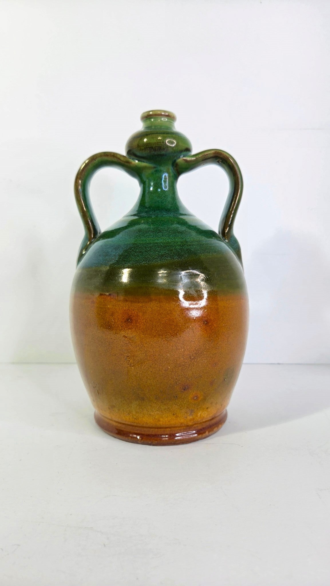 Oddly Darling Vintage handcrafted ceramic jug with two handles, featuring a forest green and amber-brown glaze.