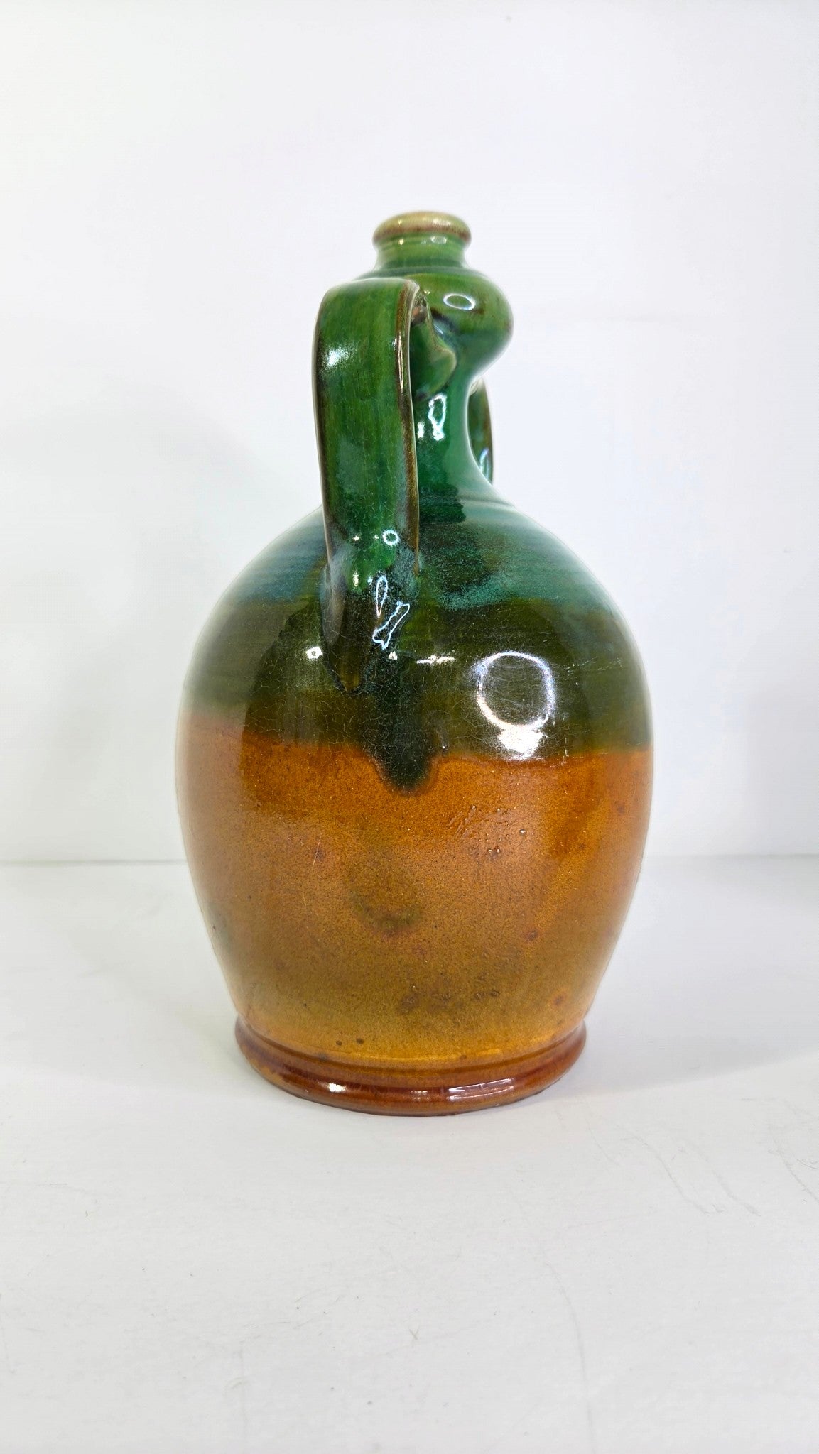 Oddly Darling Vintage handcrafted ceramic jug with a two-tone forest green and amber-brown glaze and dual handles.