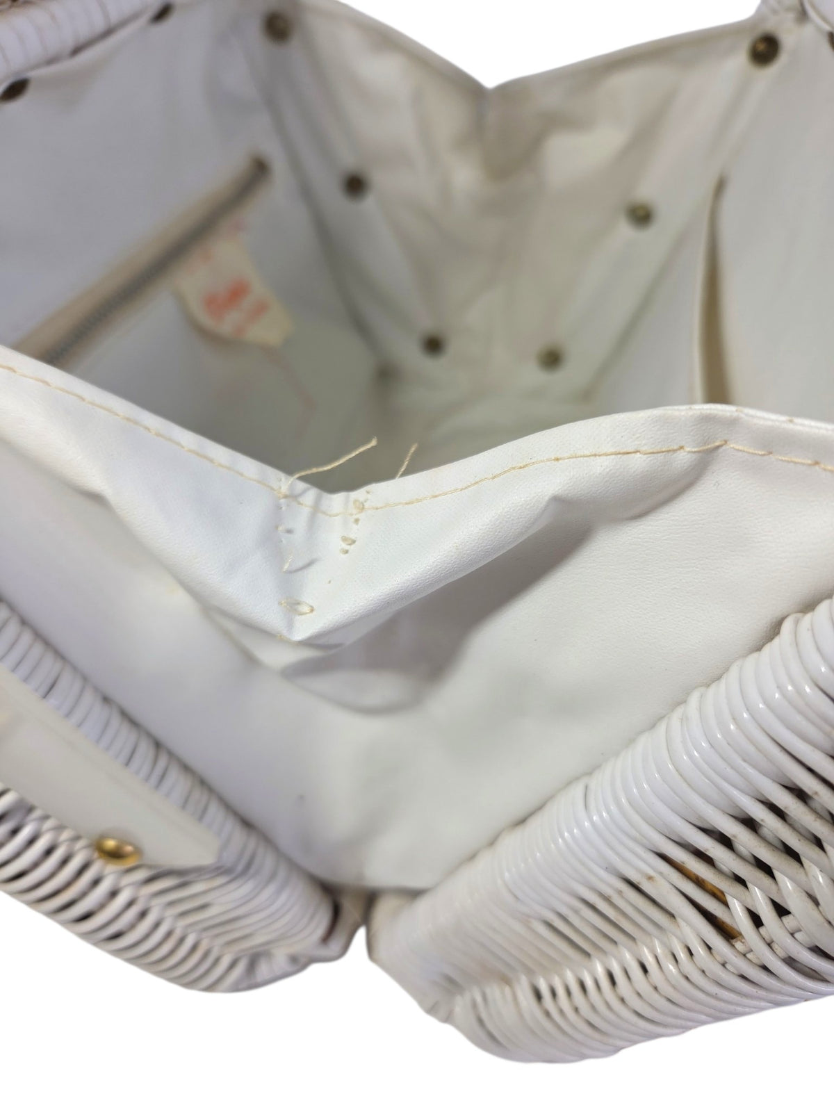 Inside corner seam of the lining that has come apart, with loose threads, next to the wicker side