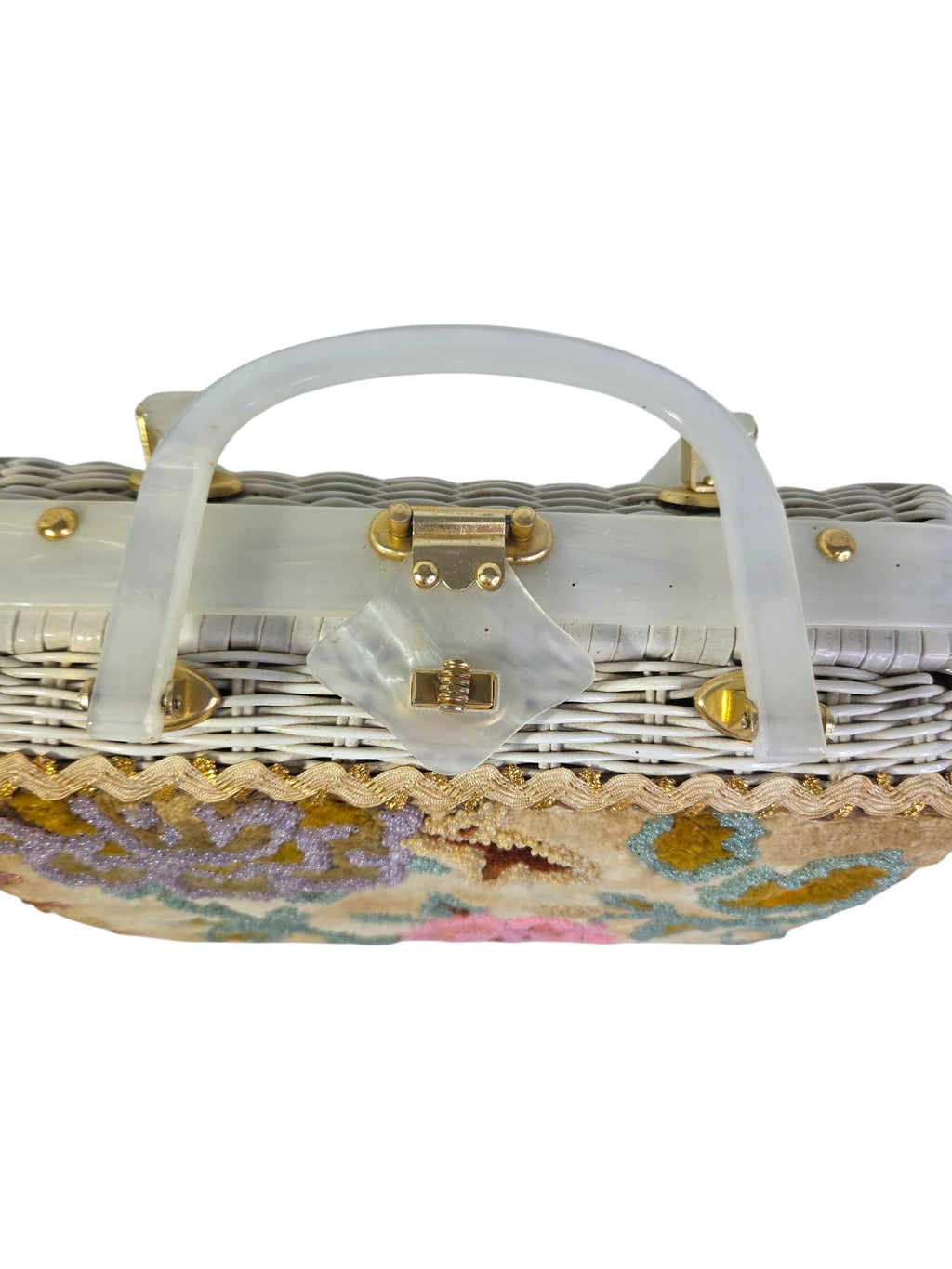 Close-up of the diamond-shaped pearlized Lucite clasp tab and gold-tone turn lock on top of the purse